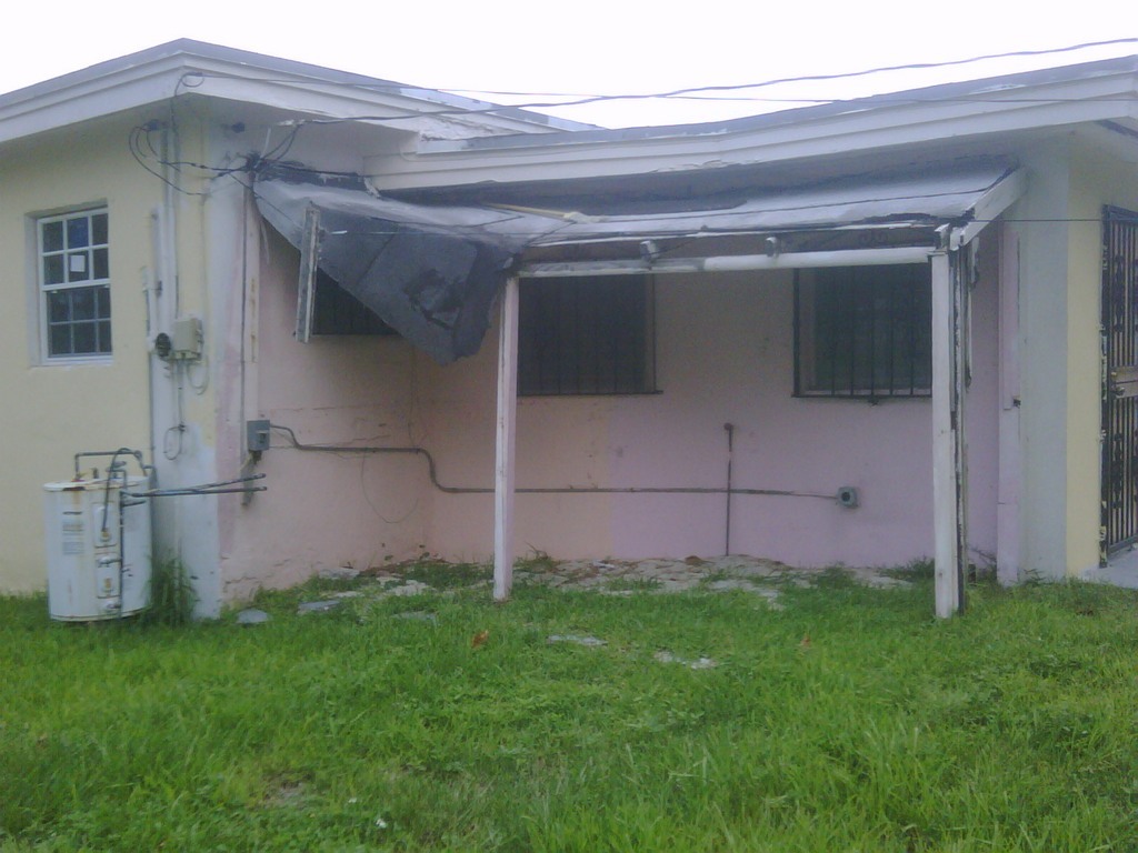 Before photo of R.E.O. property with windows & shutters compliance violations