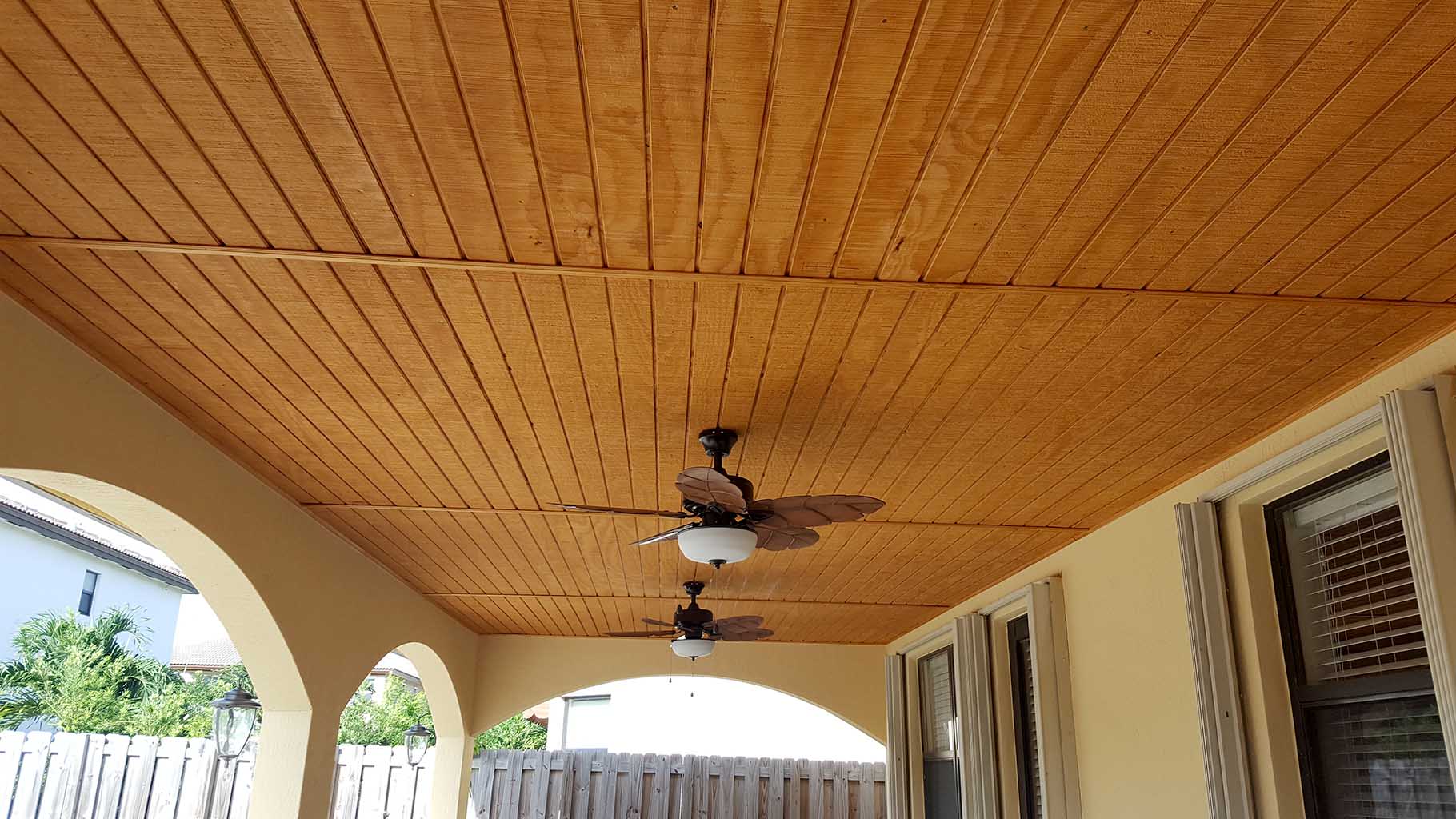 Covered patio ceiling finished with wood trim & ceiling fans installed