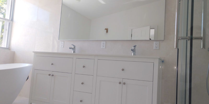 Remodeled master bathroom with freestanding bathtub and shower enclosure with sliding glass door