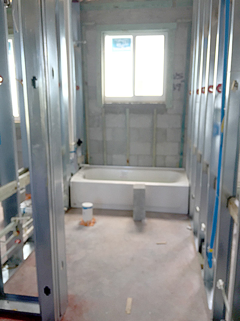 Before photo of partitions and tub in guest bathroom