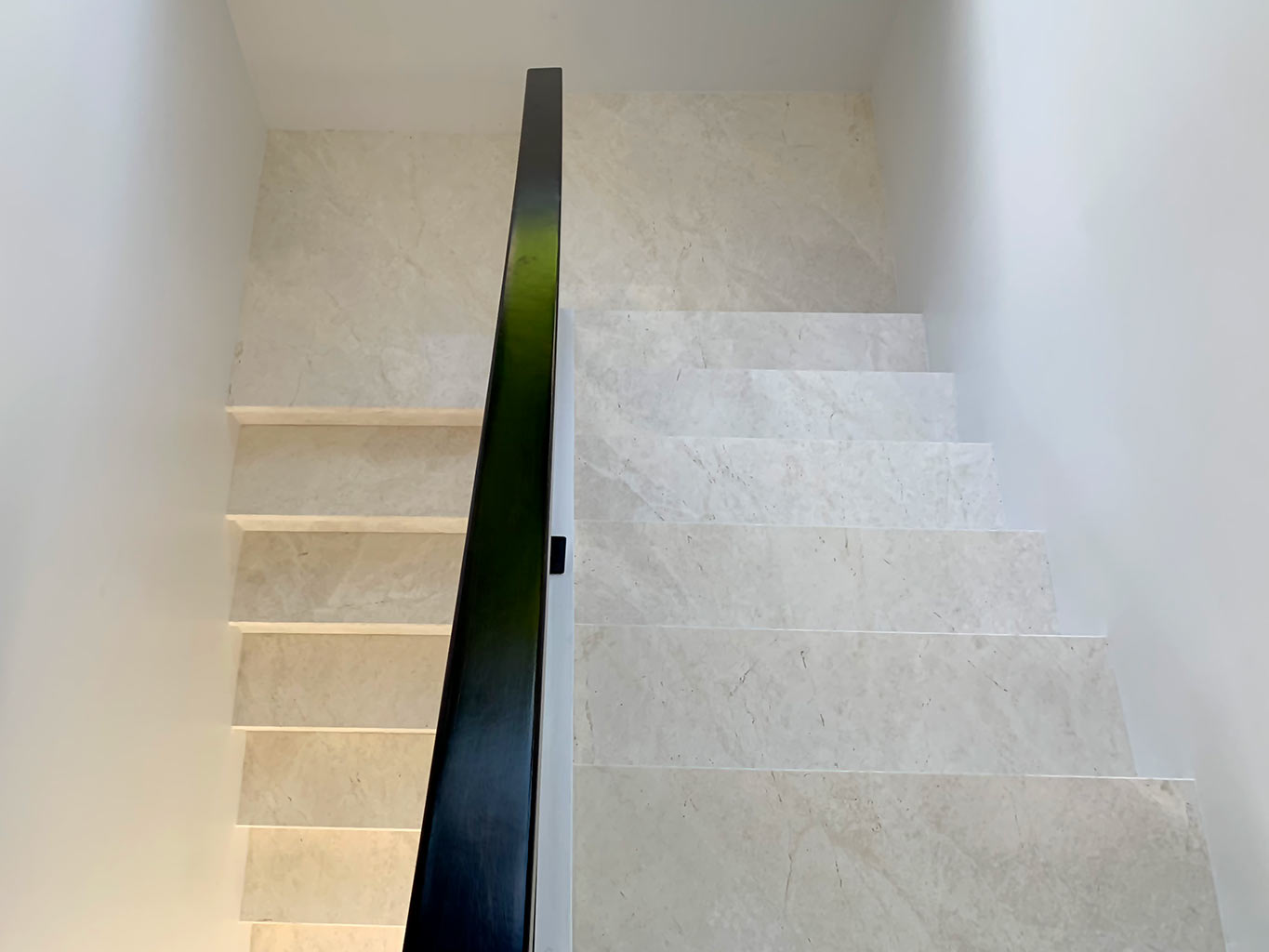 Remodeled stairway with new white marble flooring and steel handrail