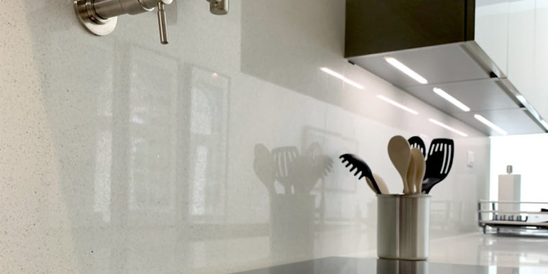 Close-up of glass cook-top, pot filler, quartz counter and backsplash