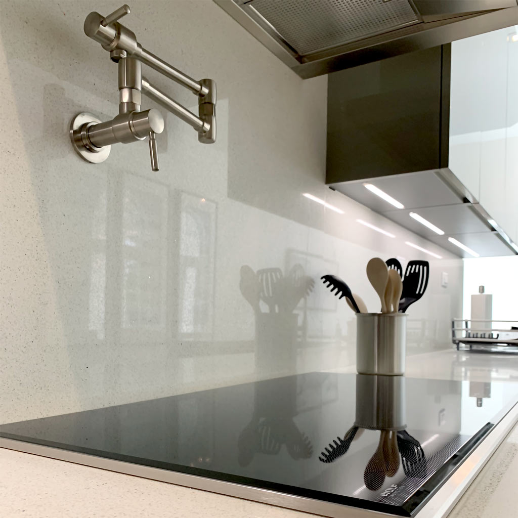 Close-up of glass cook-top, pot filler, quartz counter and backsplash