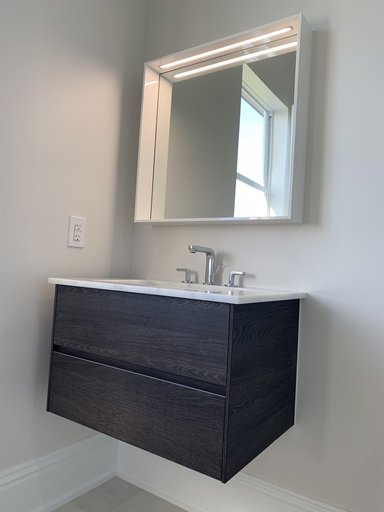 New floating vanity featuring modern mirror with built-in lighting