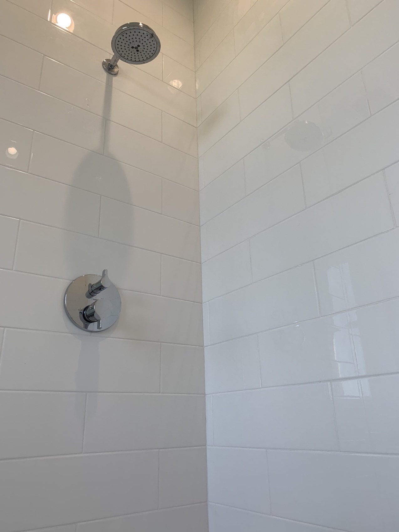 Close-up photo of subway wall tile on shower walls with chrome shower trim kit