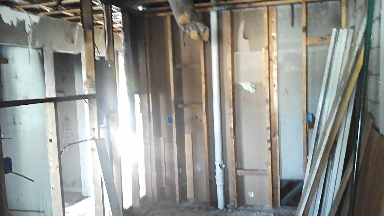 Before photo of kitchen with missing cabinets and drywall