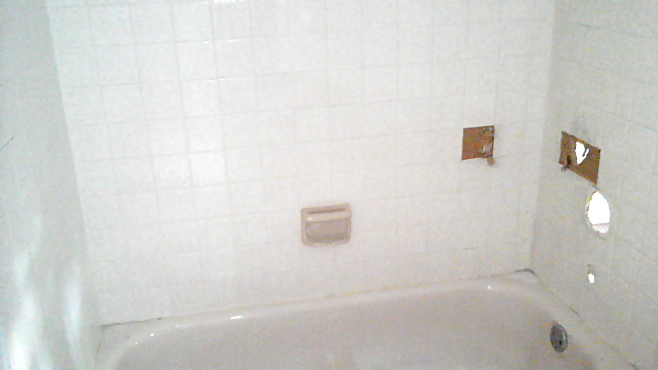 Before photo of tub with missing controls and shower wall tiles