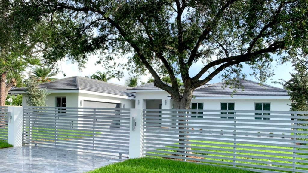 Street view of completed home with horizontal aluminum fence and gate